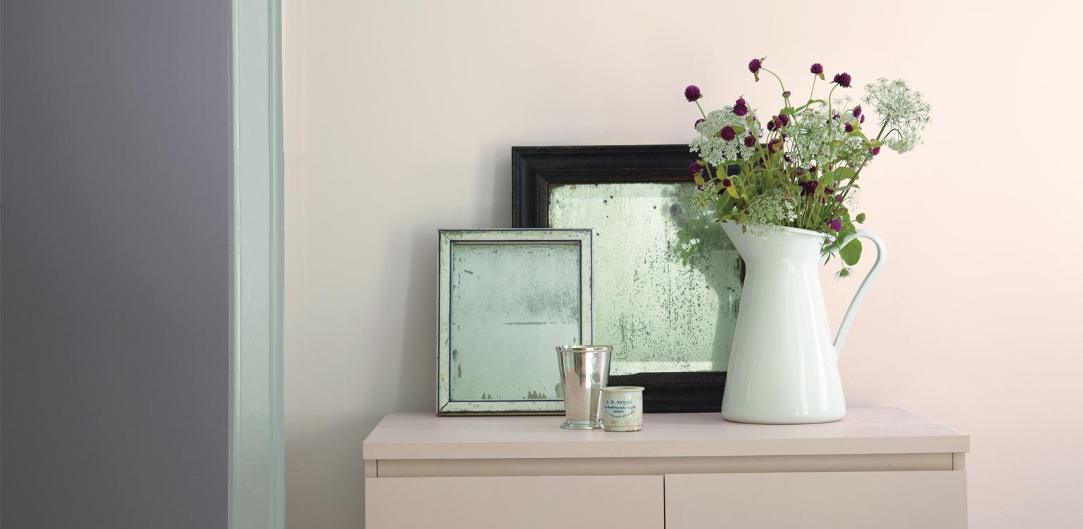 small table against wall with picture frames and vase with flowers